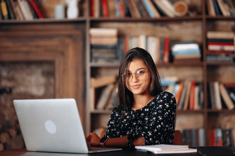 A Girl Working Diligently at a Desk with Books and Study Materials at Library